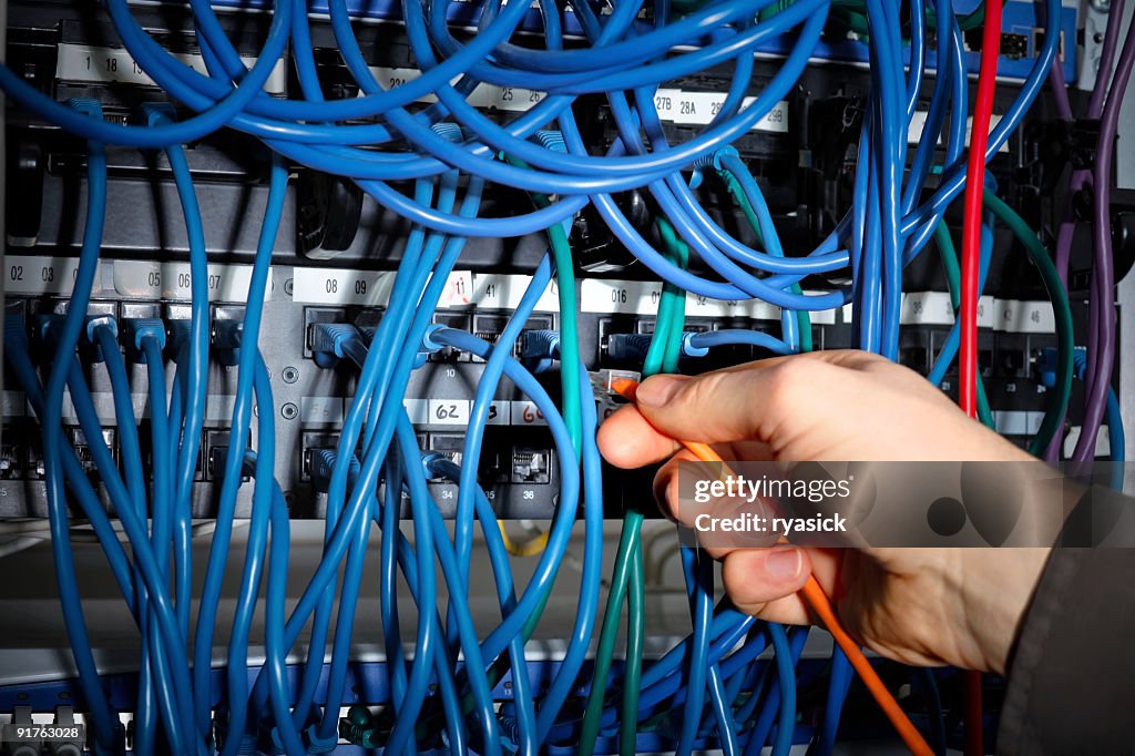 Closeup of Hand Making Cable Connections on Server Network