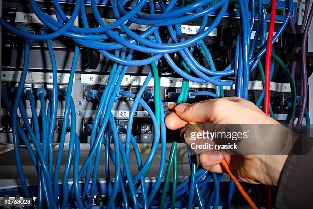 closeup of hand making cable connections on server network - modem stock pictures, royalty-free photos & images