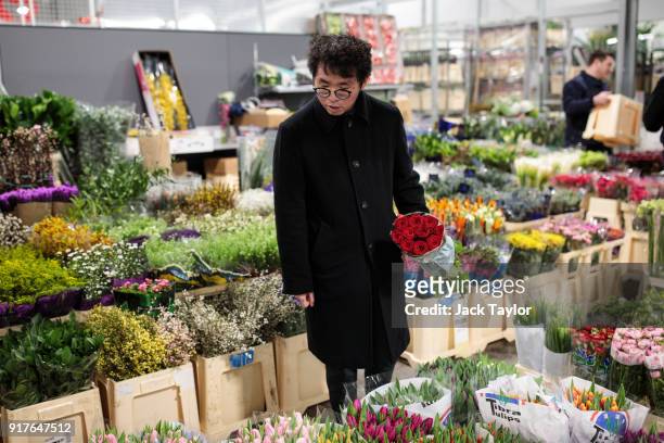 Customer looks through the flowers on display while holding a bunch of roses at New Covent Garden Flower Market ahead of Valentine's Day on February...