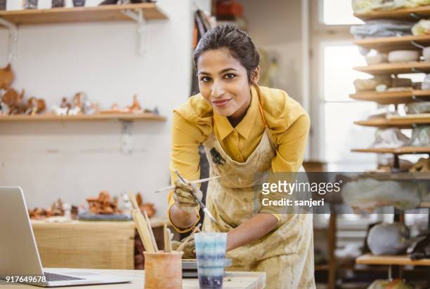 portret van een jonge vrouw maken van aardewerk, met behulp van laptop - aardewerk stockfoto's en -beelden