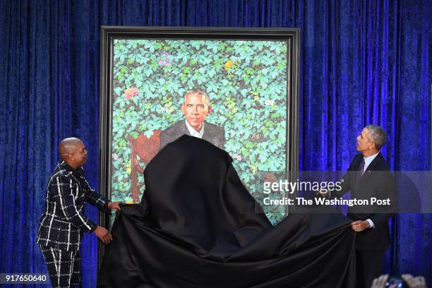 Artist, Kehinde Wiley, left, and former President Barack Obama take a cloth from Obama's presidential portrait as he and former First Lady Michelle...