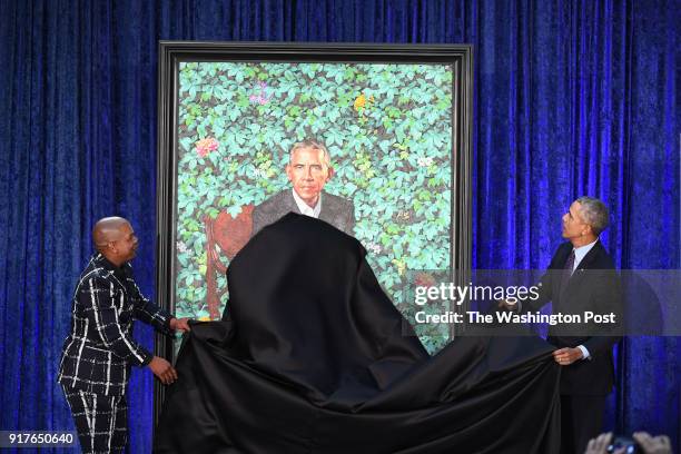 Artist, Kehinde Wiley, left, and former President Barack Obama take a cloth from Obama's presidential portrait as he and former First Lady Michelle...