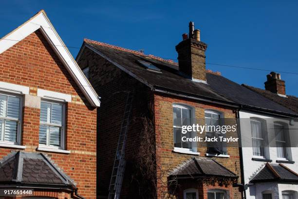 Decorator leans out of a window as he paints a house's window frame on February 12, 2018 in Weybridge, United Kingdom. Surrey County Council have...