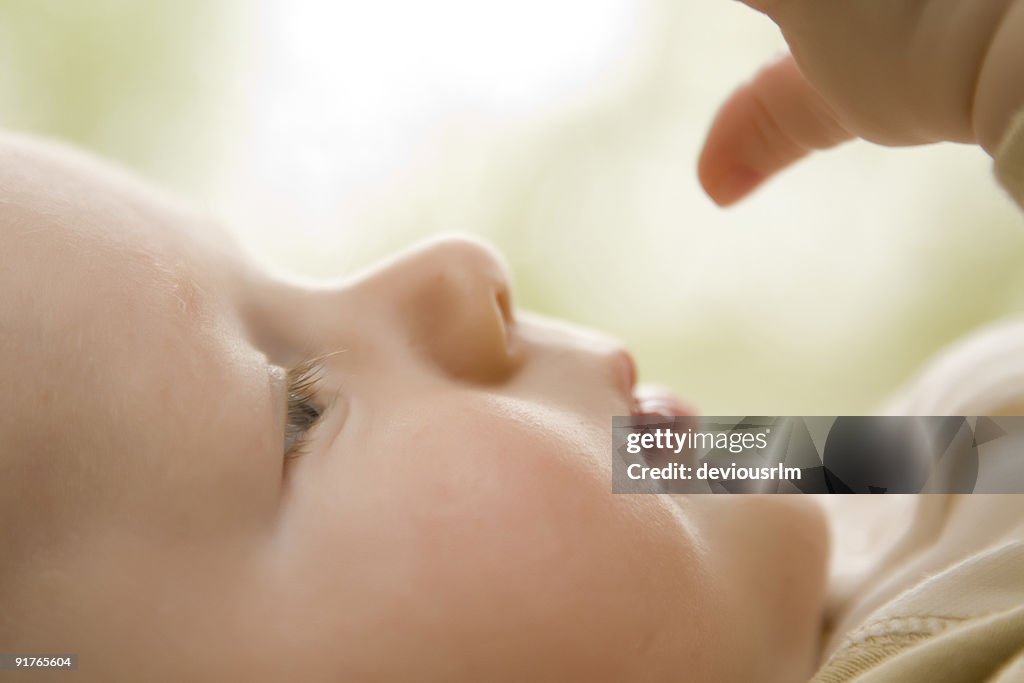 Baby profile checking out hand, soft focus