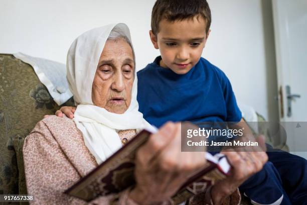 Very old Muslim woman at home reading with little boy