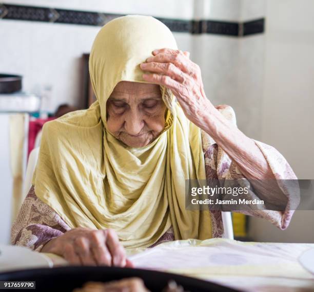 Very old Muslim woman at home eating lunch