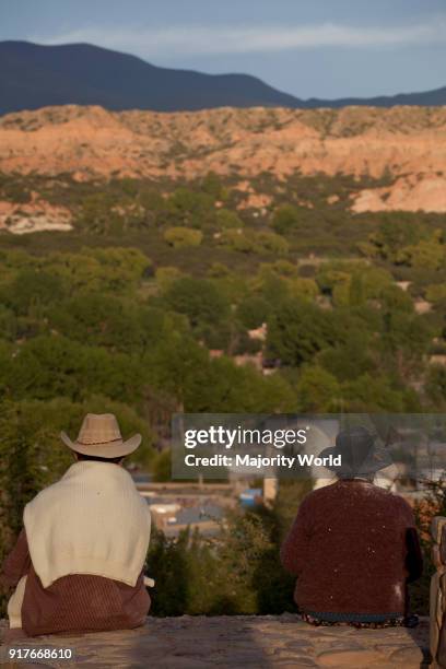 Local couple sit with views of Quebrada de Humahuaca in Jujuy province in the Andes region of Argentina, South America.