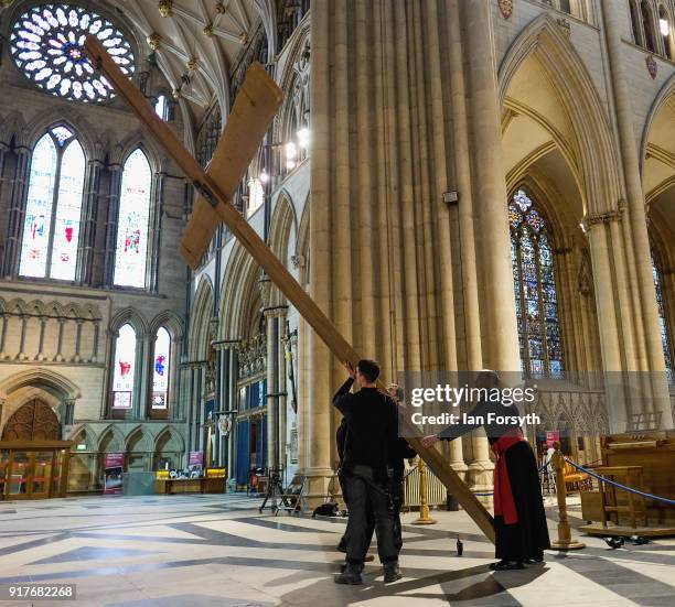 Canon Michael Smith along with joiners from York Minster's Works Department manoeuvre a wooden cross as it is suspended from York Minster's Central...