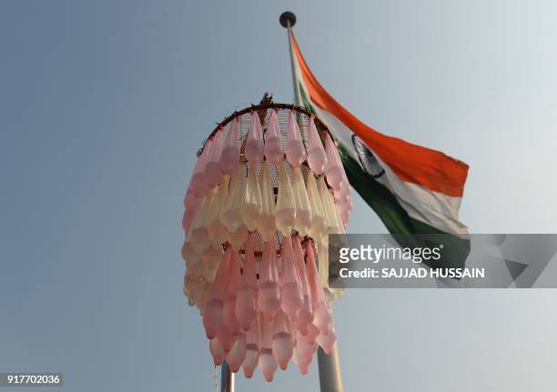 Condoms filled with water hang from a display during an event to mark International Condom Day in New Delhi on February 13, 2018. The event was...