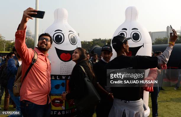 Indian visitors take selfies with volunteers dressed as condoms during an event to mark International Condom Day in New Delhi on February 13, 2018....