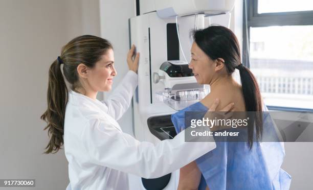 weiblichen frauenarzt hilft eine gastgeberin in positionieren für eine mammographie erhalten - mammographie stock-fotos und bilder
