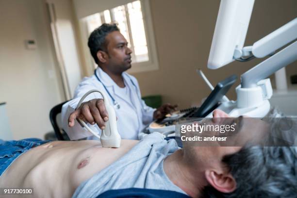indian doctor doing a heart ultrasound to a middle aged male patient - diagnostic aid stock pictures, royalty-free photos & images