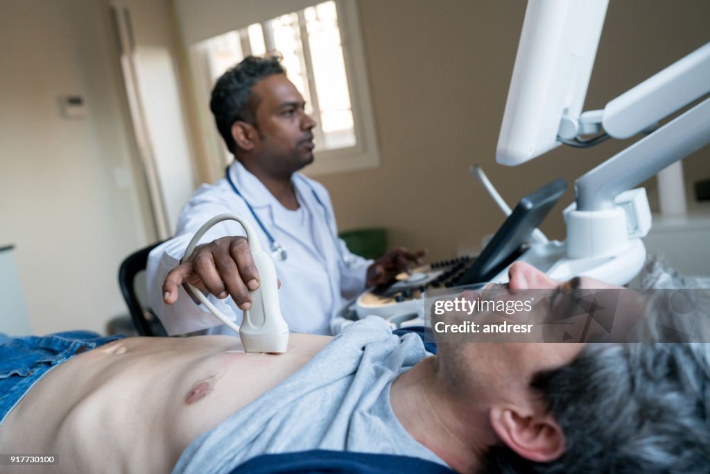 Médico indiano fazendo um ultrassom do coração de um paciente do sexo masculino de meia idade