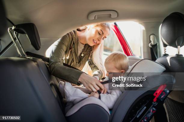 haar zoon aanbrengend zijn autostoeltje - mum sitting down with baby stockfoto's en -beelden