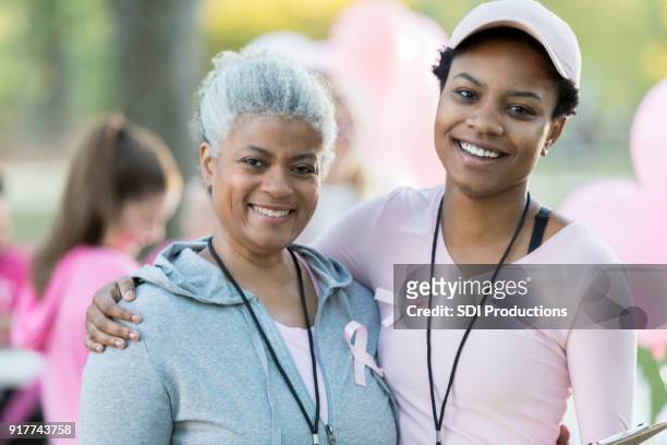 senior woman and daughter smile for camera at race for cure - young woman and senior lady in a park stock pictures, royalty-free photos & images