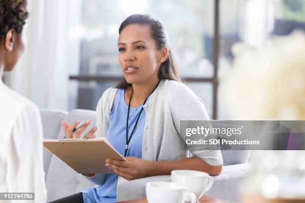 vrouwelijke psychiater bespreekt iets met vrouwelijke patiënt - translation stockfoto's en -beelden