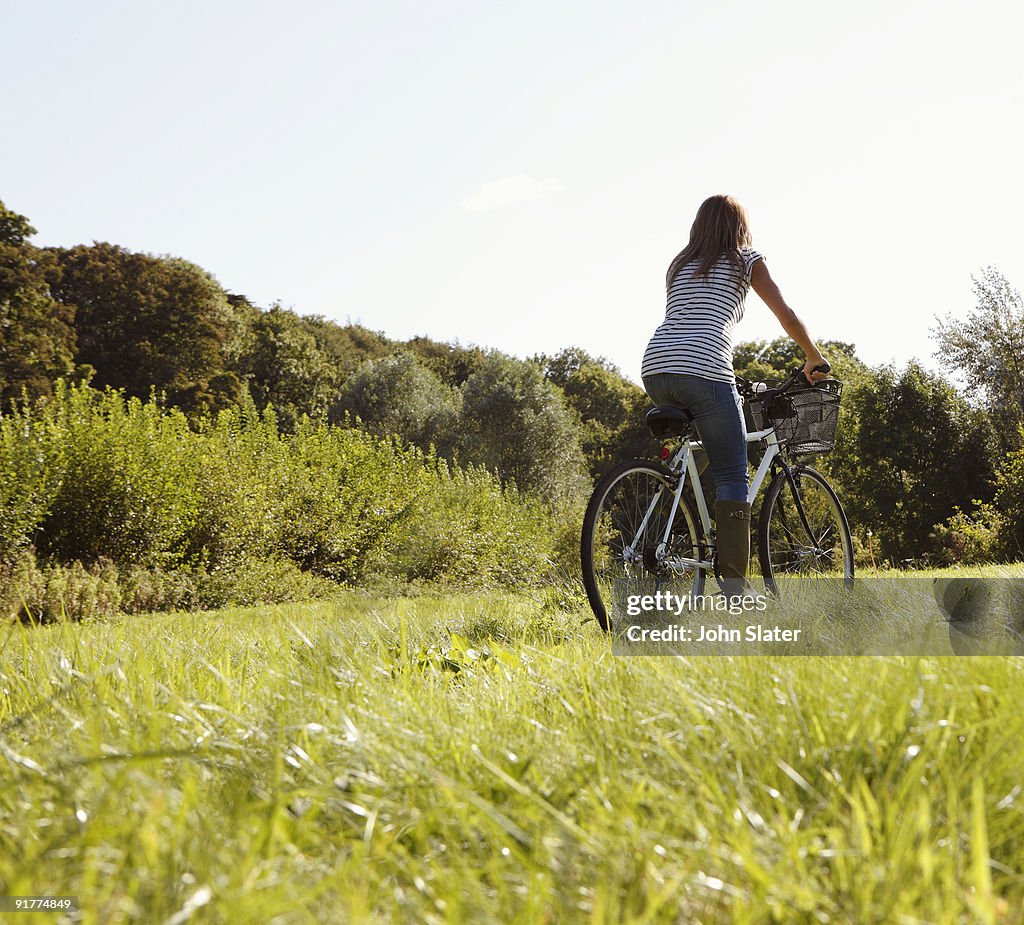 Rear view of woman cycling through field