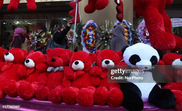 Palestinian women walk next to a shop displaying red teddy bears on the eve of Valentine's Day in Gaza City ,13 February 2018.