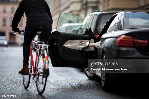 Posed scene of a driver who suddenly opens the door of the car during a cyclist passes the car on February 13, 2018 in Berlin, Germany.