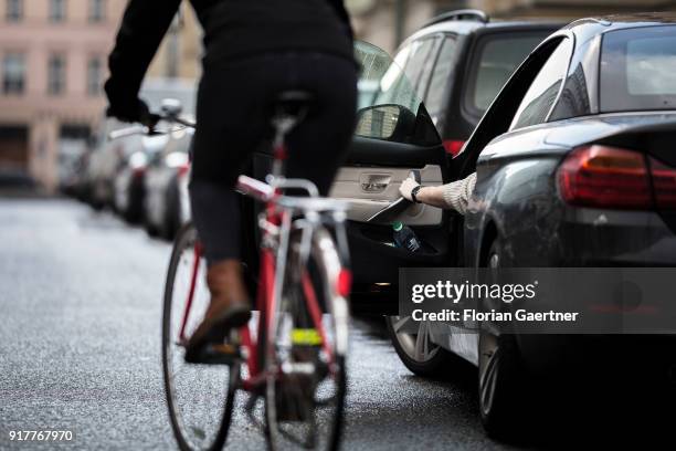 Posed scene of a driver who suddenly opens the door of the car during a cyclist passes the car on February 13, 2018 in Berlin, Germany.