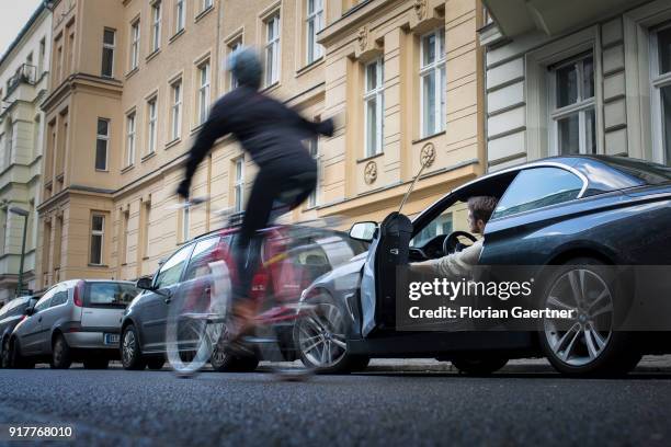 Posed scene of a driver who suddenly opens the door of the car during a cyclist passes the car on February 13, 2018 in Berlin, Germany.