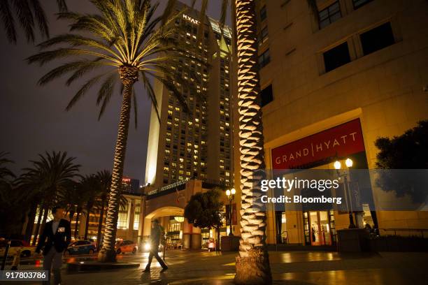 Pedestrians pass in front of the Manchester Grand Hyatt Hotel at night in San Diego, California, U.S., on Sunday, Feb. 11, 2018. Hyatt Hotels Corp....