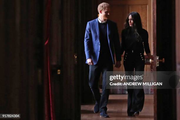 Britain's Prince Harry and his fiancée US actress Meghan Markle walk through the corridors of the Palace of Holyroodhouse on their way to a reception...