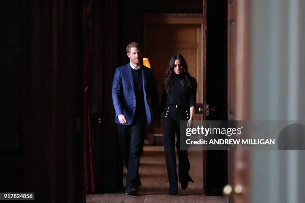 Britain's Prince Harry and his fiancée US actress Meghan Markle walk through the corridors of the Palace of Holyroodhouse on their way to a reception...