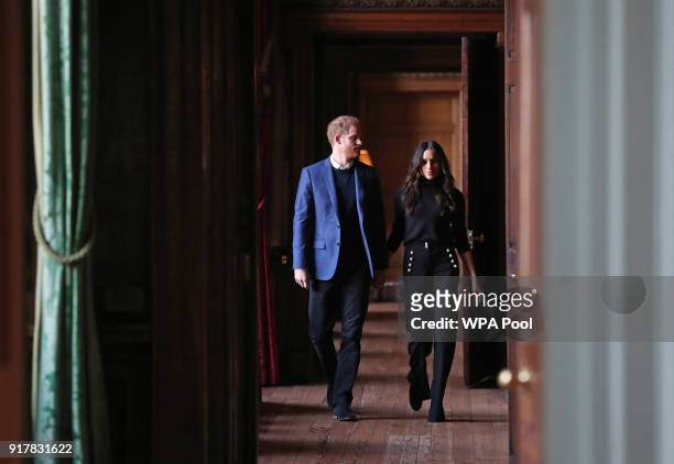 Prince Harry and Meghan Markle walk through the corridors of the Palace of Holyroodhouse on their way to a reception for young people at the Palace...
