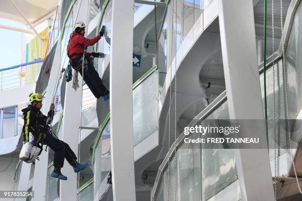 Workers clean windows on the upper deck of US shipowner Royal Caribbeans new Oasis-class cruise ship, Symphony of the Seas, the largest passenger...