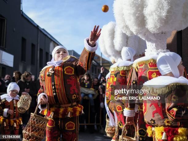 Boy dressed as a "Gille", the oldest and principal participants in the Carnival of Binche in Belgium, wearing their white feather hat, throws an...