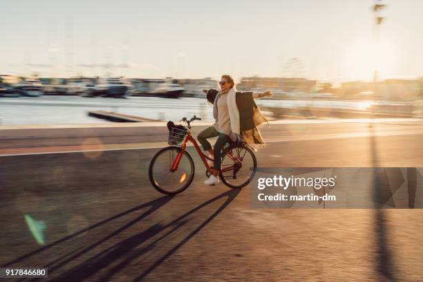 young woman riding a bicycle with hands outstretched - winter relaxation stock pictures, royalty-free photos & images