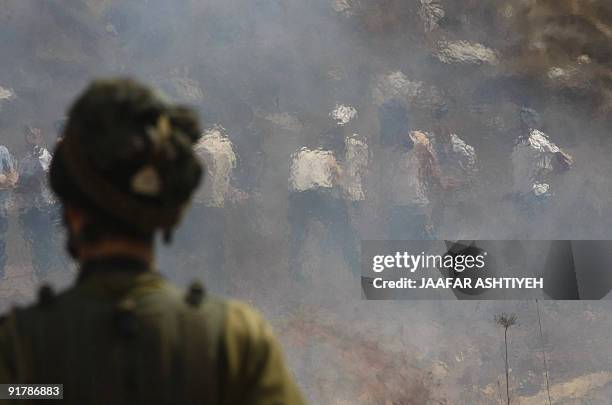An Israeli soldier faces Palestinian youths demonstrating against the closure of a road that leads to the West Bank village of Qarut, near Nablus, on...