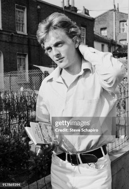 Portrait of English actor David Hemmings on the set of the film 'Blow-Up' , London, England, 1965. He holds a copy of 'The Camper's Pocket Book'.