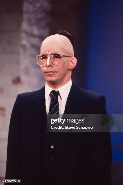 View of American actor and comedian Richard Belzer, in a bald cap, as he performs during an skit, Los Angeles, California, 1983.