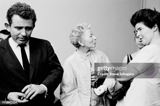 Backstage at Carnegie Hall, American author Norman Mailer smokes a cigarette, with journalist Mary Hemingway and Mailer's wife, Lady Jeanne Campbell...