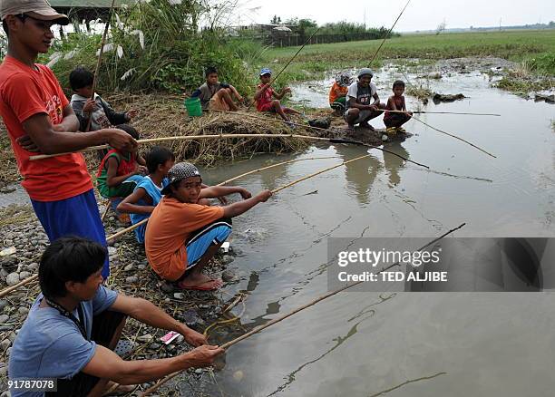 Residents affected by floods try to catch fish in the town of Gerona, Tarlac province north of Manila on October 11, 2009 two days after massive...