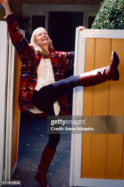 View of American actress Susan Blakely as she kicks out one leg, her head tilted back, as she stands in an open gateway, Los Angeles, California,...