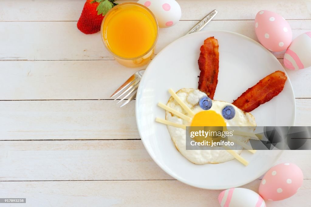 Easter breakfast, table scene with bunny face over white wood
