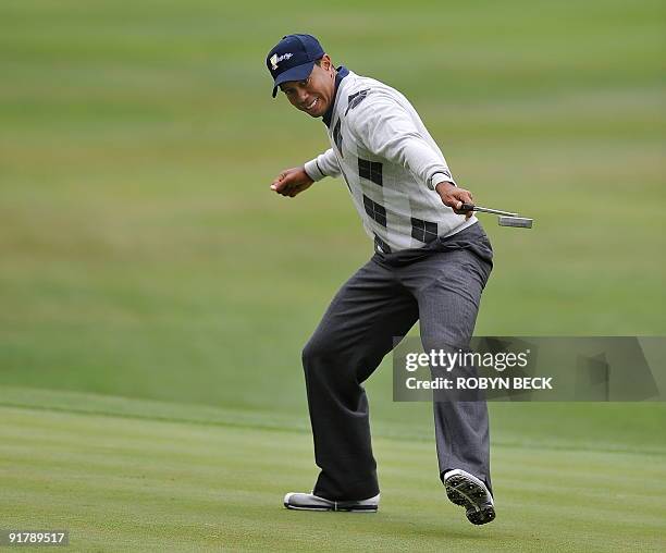 Team member Tiger Woods watches his putt roll toward the hole for a birdie on the 17th green, in the third round - foursome matches at the Presidents...