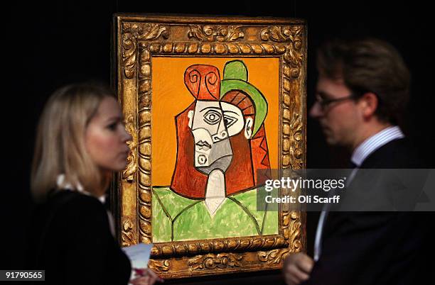 Couple chat in front of a painting by Pablo Picasso entitled 'Tete de Femme au Chapeau Vert' in Sotheby's auction house on October 12, 2009 in...