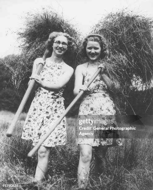 Two young women helping with the harvest on a farm in Ripley, Surrey, circa 1935.