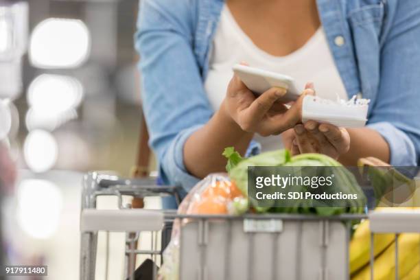 onherkenbaar vrouw maakt gebruik van mobiele app in supermarkt - over press call stockfoto's en -beelden