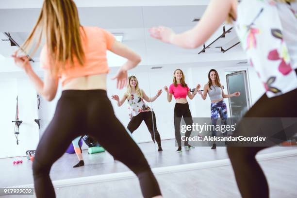 groep van schattige lachende vrouwtjes opleiding zumba voor de spiegel in sportschool - buikdanseres stockfoto's en -beelden