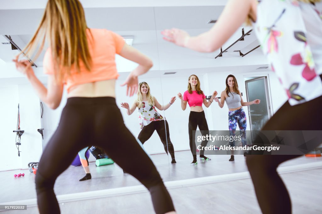 Group of Cute Smiling Females Training Zumba in front of the Mirror in Gym