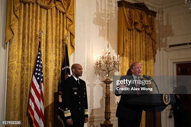 President Donald Trump speaks as Surgeon General Jerome Adams looks on during a reception in the East Room of the White House February 13, 2018 in...