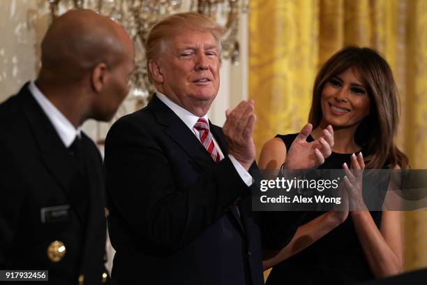 President Donald Trump and first lady Melania Trump applaud as Surgeon General Jerome Adams looks on during a reception in the East Room of the White...