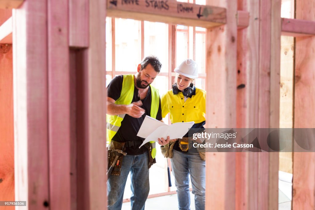 Male and female construction workers discuss the building plans inside the building site