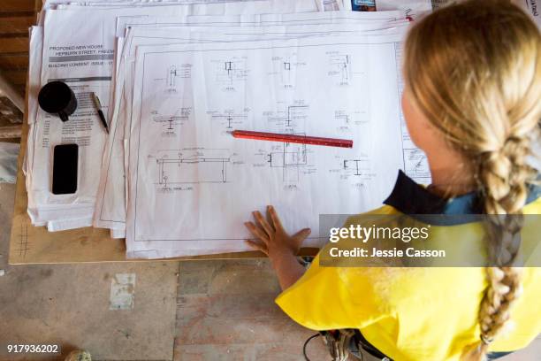 a female construction worker looks at site plans - bauingenieurwesen stock-fotos und bilder