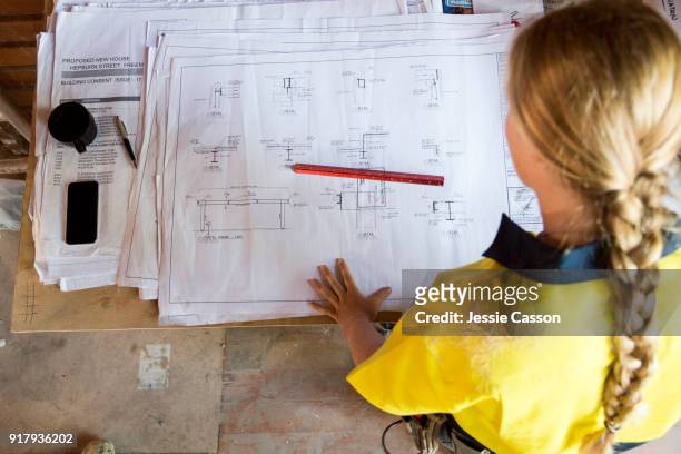 a female construction worker looks at site plans - construction planning stockfoto's en -beelden
